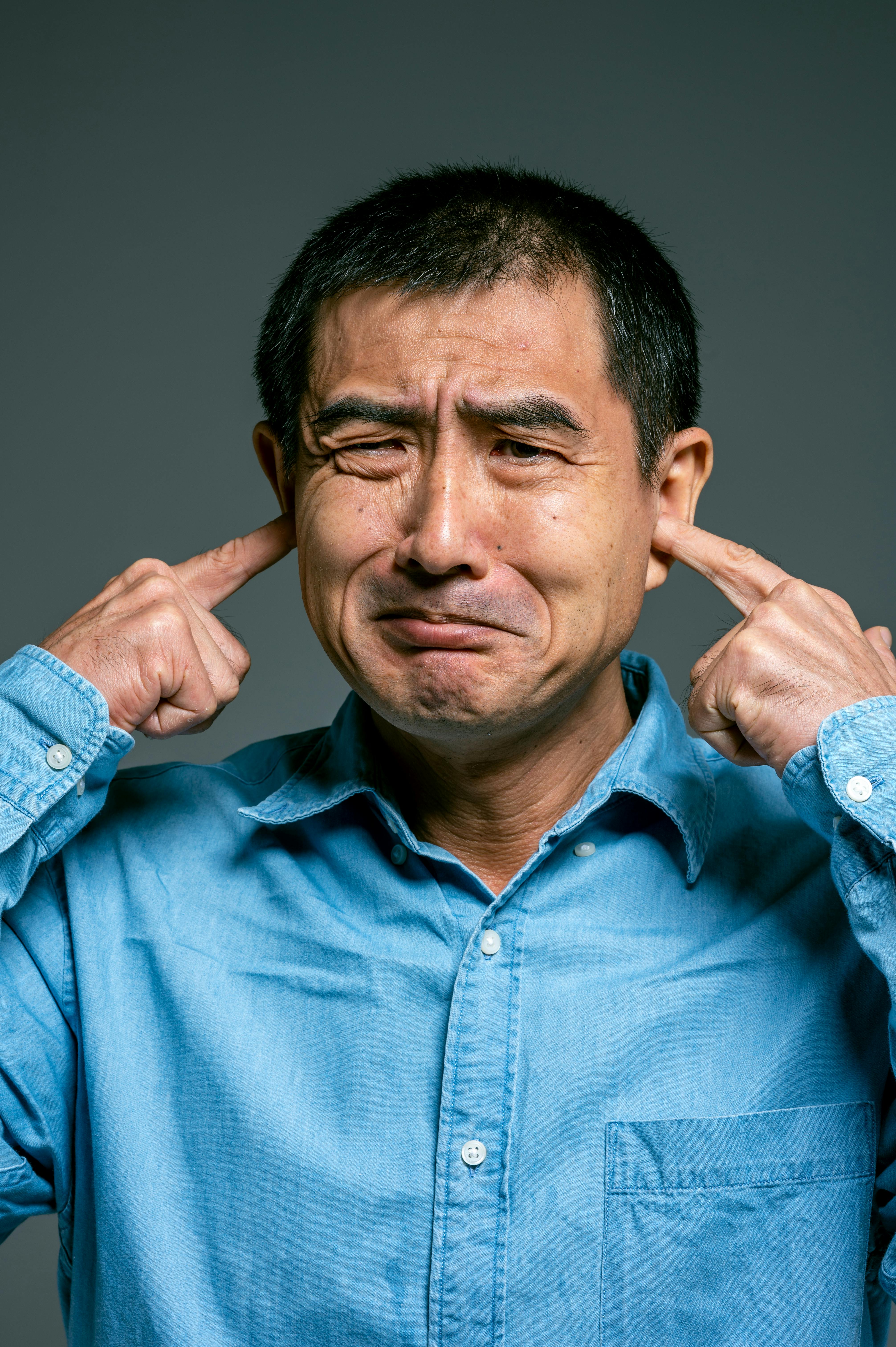 Man covering his ears because of loud neighbors.